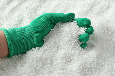 Farmer taking pellets of ammonium nitrate from pile, closeup. mineral fertilizer