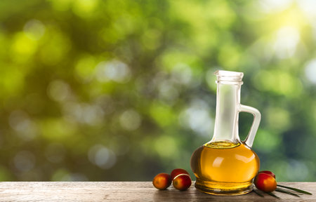 Palm oil in glass jug, tropical leaf and fruits on wooden table, space for text. bokeh effectの写真素材