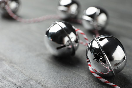 Shiny silver sleigh bells on grey stone table, closeup. Space for textの写真素材