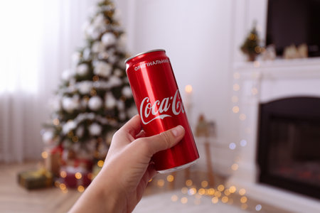 MYKOLAIV, UKRAINE - JANUARY 13, 2021: Woman holding can of Coca-Cola in room with Christmas tree, closeupのeditorial素材