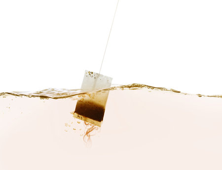 Dipping of tea bag into hot water against white backgroundの写真素材