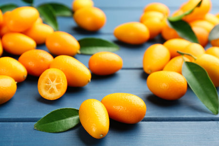 Fresh ripe kumquats and leaves on blue wooden table, closeupの写真素材