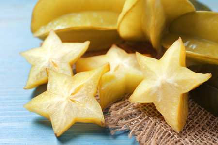 Cut and whole carambolas on turquoise wooden table, closeupの写真素材