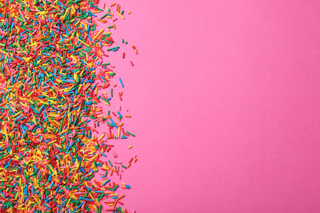 Bright colorful sprinkles on pink background, flat lay with space for text. Confectionery decorの写真素材