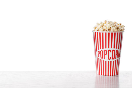 Delicious popcorn in paper cup on white wooden tableの写真素材