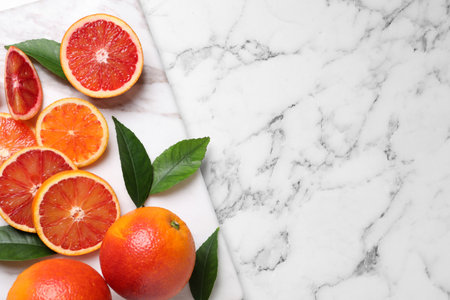 Whole and cut red oranges on white marble table, top view. Space for textの写真素材