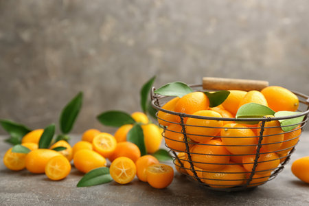 Fresh ripe kumquats in bowl on gray table, space for textの写真素材
