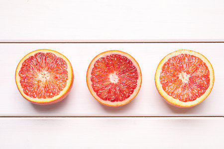 Halves of ripe red oranges on white wooden table, flat layの写真素材