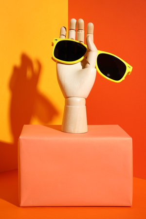 Wooden mannequin hand with stylish sunglasses on color backgroundの写真素材