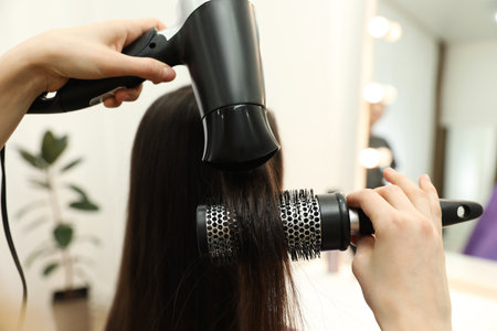 Stylist drying client's hair in beauty salon, closeupの写真素材