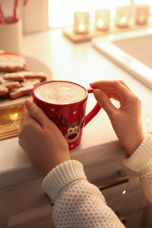 Woman holding cup with hot drink in kitchen, closeupの写真素材