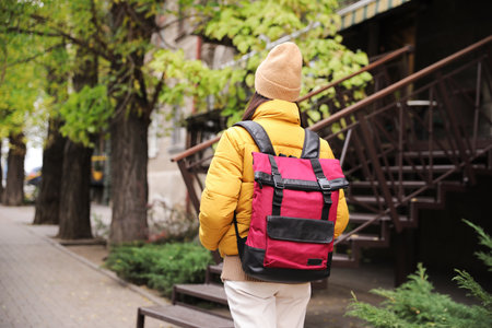 Female tourist with travel backpack on city street, back view. urban trip