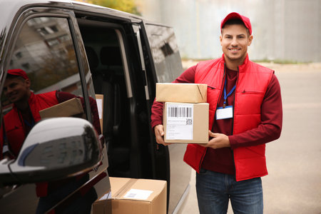 Courier with parcels near delivery van outdoorsの写真素材