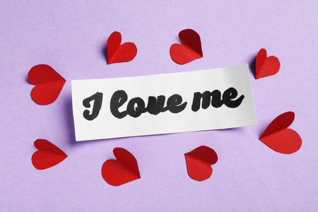 Paper with handwritten phrase I Love Me and red hearts on violet background, top viewの写真素材