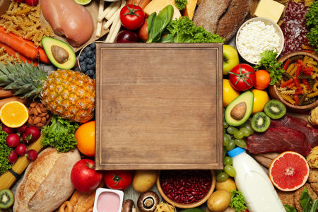 Wooden board on pile of different food products, top view with space for text. Healthy balanced dietの写真素材