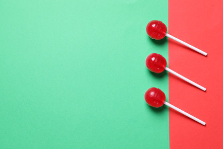 Three red lollipops on color background, flat lay. Space for textの写真素材