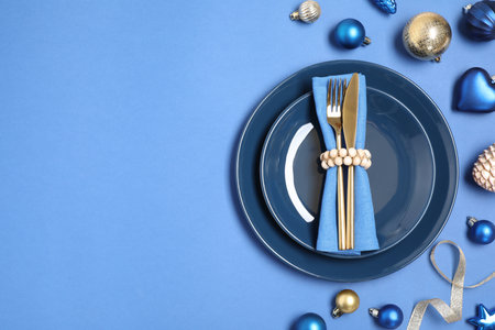 Beautiful table setting with Christmas ornament on blue background, flat lay. Space for textの写真素材