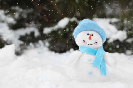 Cute small snowman toy on snow outdoors, space for textの写真素材