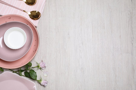 Flat lay composition with beautiful dishware and roses on white wooden table. Space for textの写真素材