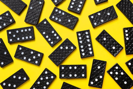 Black domino tiles on yellow background, flat layの写真素材