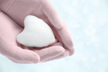 Woman holding heart shaped snowball in hands, closeupの写真素材