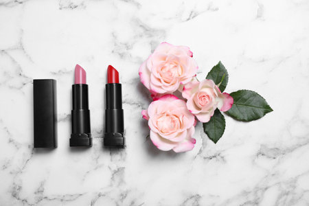 Different lipsticks and beautiful flowers on white marble table, flat layの写真素材