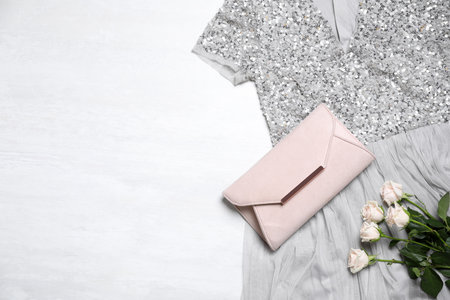 Elegant dress, pink bag and beautiful roses on white background, flat lay. Space for textの写真素材