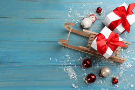 Beautiful Christmas composition with miniature sleigh on light blue wooden table, flat lay. Space for textの写真素材