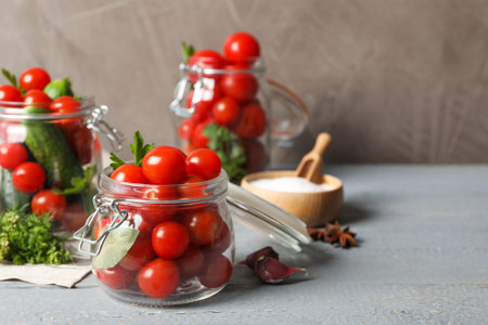 Pickling jars with fresh ripe vegetables on gray wooden tableの写真素材