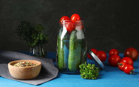 Pickling jar with fresh ripe vegetables and spices on blue wooden tableの写真素材