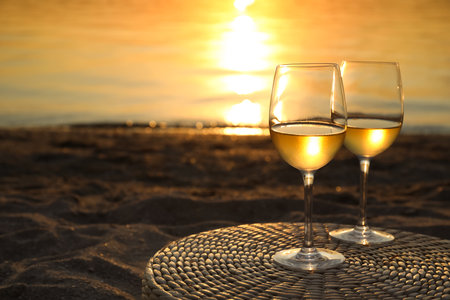 Glasses of delicious wine on riverside at sunsetの写真素材
