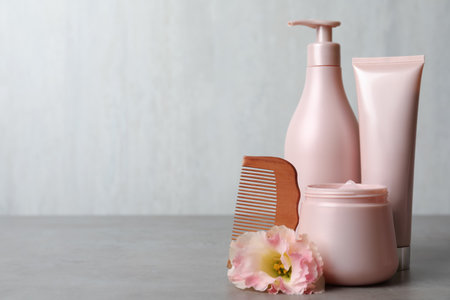 Different hair products, flower and wooden comb on gray table. Space for textの写真素材
