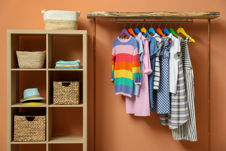 Different child's clothes hanging on rack in roomの写真素材