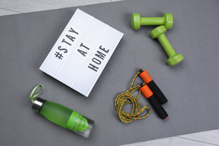 Sport equipment and lightbox with hashtag STAY AT HOME on gray yoga mat, flat lay.の写真素材