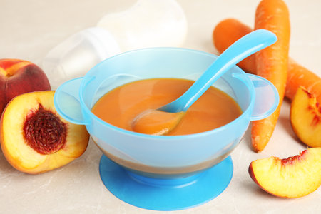 Baby food in bowl and fresh ingredients on light gray tableの写真素材