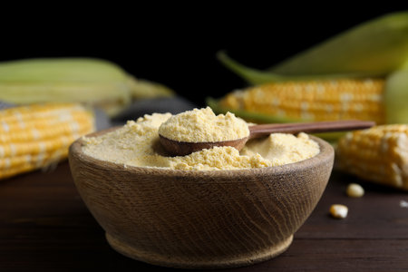 Corn flour in bowl and fresh cobs on wooden tableの写真素材
