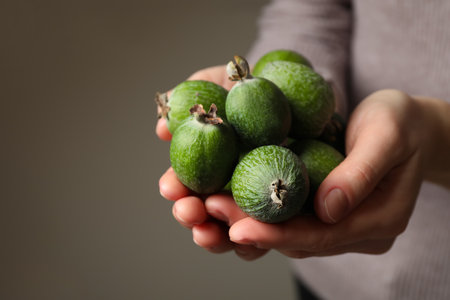 Woman holding fresh green feijoa fruits on gray background, closeupの写真素材