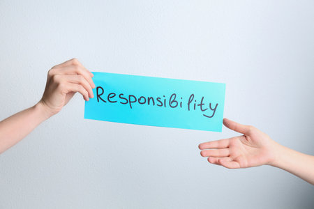 Woman giving light blue paper sheet with word Responsibility to colleague on white background, closeupの写真素材