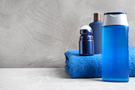 Cosmetic products and towel on light gray marble table, space for text. Men's hygiene