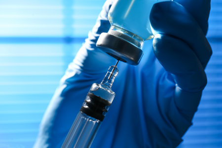 Woman filling syringe with vaccine from vial on blurred background, closeupの写真素材