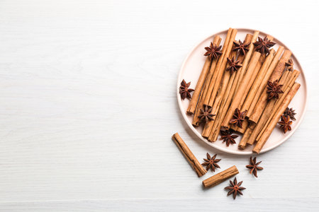 Aromatic cinnamon sticks and anise on white wooden table, flat lay. Space for textの写真素材