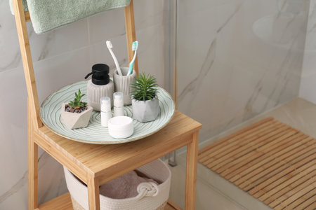 Holder with toothbrushes, different toiletries and plants on wooden rack in bathroom. Space for textの写真素材