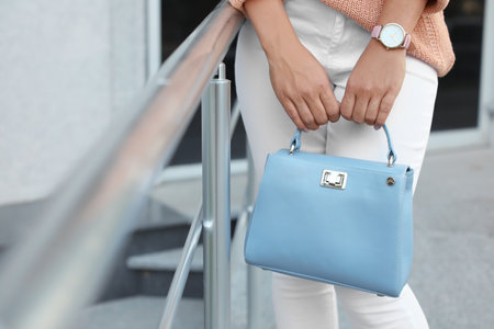 Young woman with stylish light blue bag near railing outdoors, closeupの写真素材
