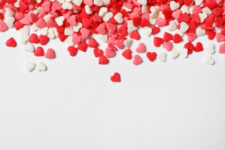 Bright heart shaped sprinkles on white background, view from above. Space for textの写真素材