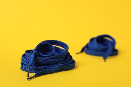 Blue shoe laces on yellow background. Space for textの写真素材