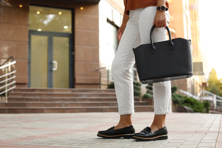 Young woman with stylish black bag on city street, closeupの写真素材
