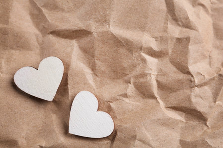 White wooden hearts on crumpled kraft paper, flat lay with space for text. St. Valentine's dayの写真素材