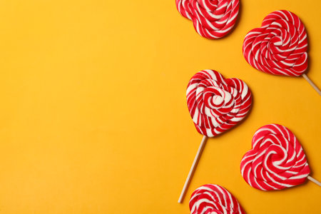 Sweet heart shaped lollipops on orange background, flat lay with space for text. Valentine's day celebrationの写真素材