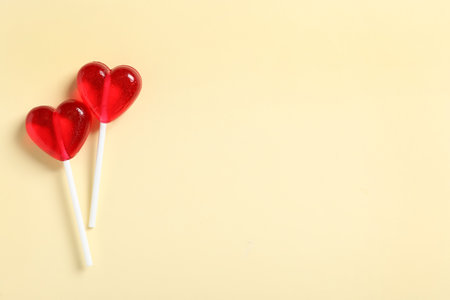 Sweet heart shaped lollipops on beige background, flat lay with space for text. Valentine's day celebrationの写真素材