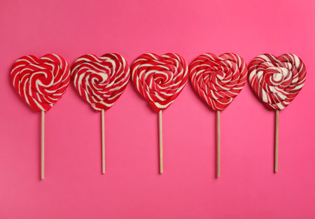 Sweet heart shaped lollipops on pink background, flat lay. Valentine's day celebrationの写真素材